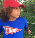 Boy at baseball field in an Atta Boy tshirt by Tribe & Trade. 