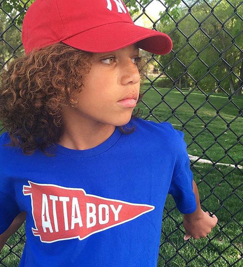 Boy at baseball field in an Atta Boy tshirt by Tribe & Trade. 